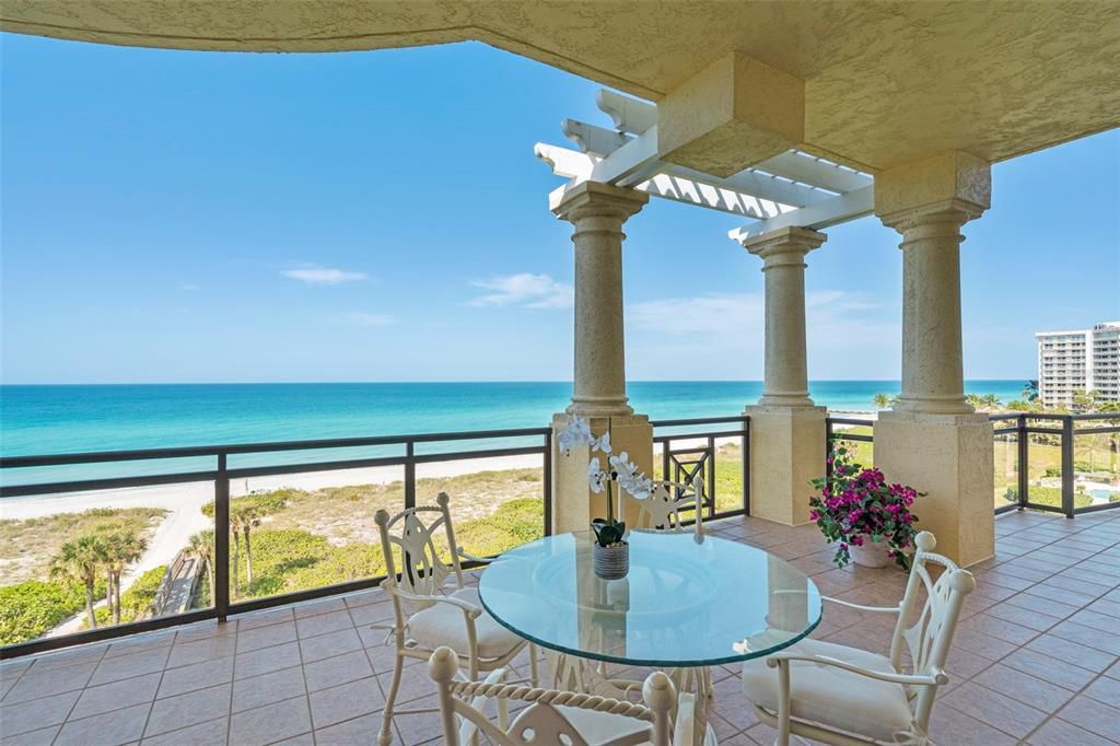 Ocean-view balcony of a Longboat Key luxury condominium featuring a glass dining table and panoramic views