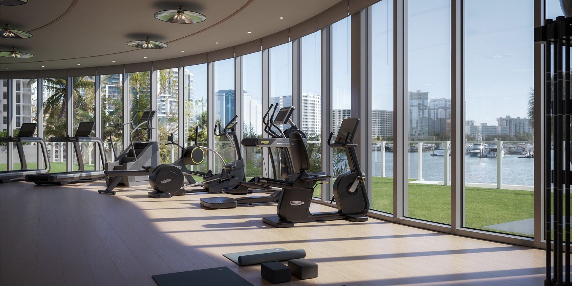 Modern fitness center at Amara on Sarasota Bay featuring cardio and strength equipment, floor-to-ceiling windows, and views of the waterfront and downtown Sarasota.