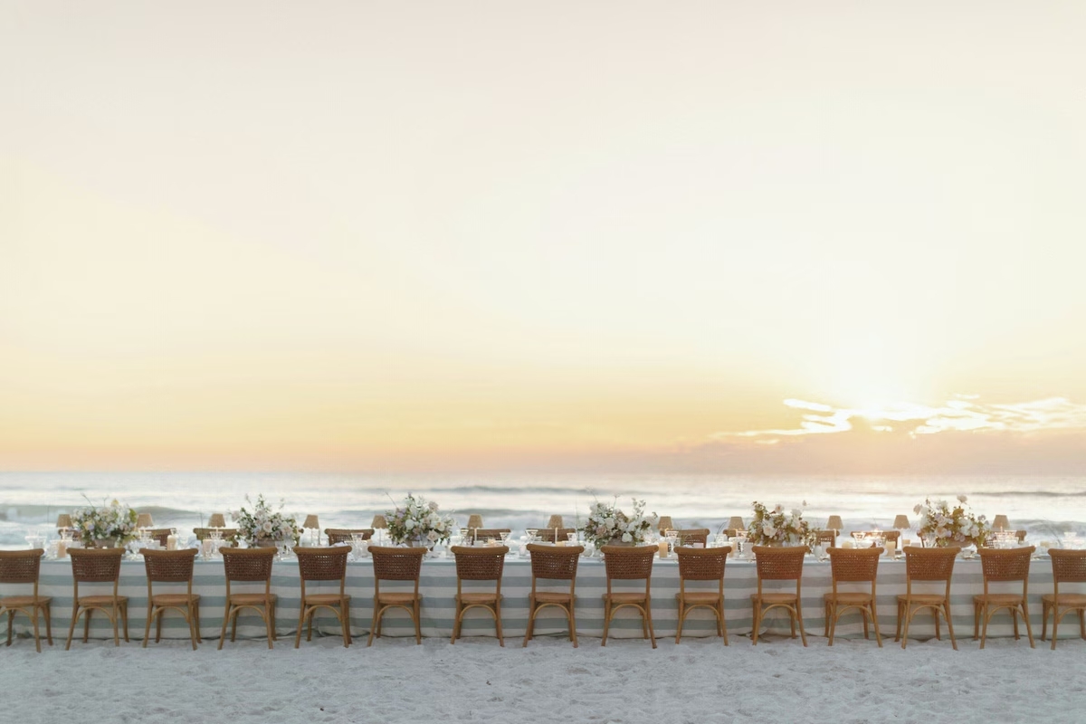 Beachside dining and social gathering setup at St. Regis Longboat Key with tables arranged along the shoreline at sunset.