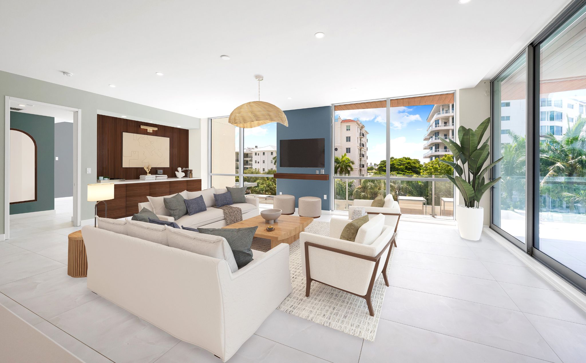 Bright living room with modern furnishings, large windows, and balcony views surrounded by lush tropical landscaping