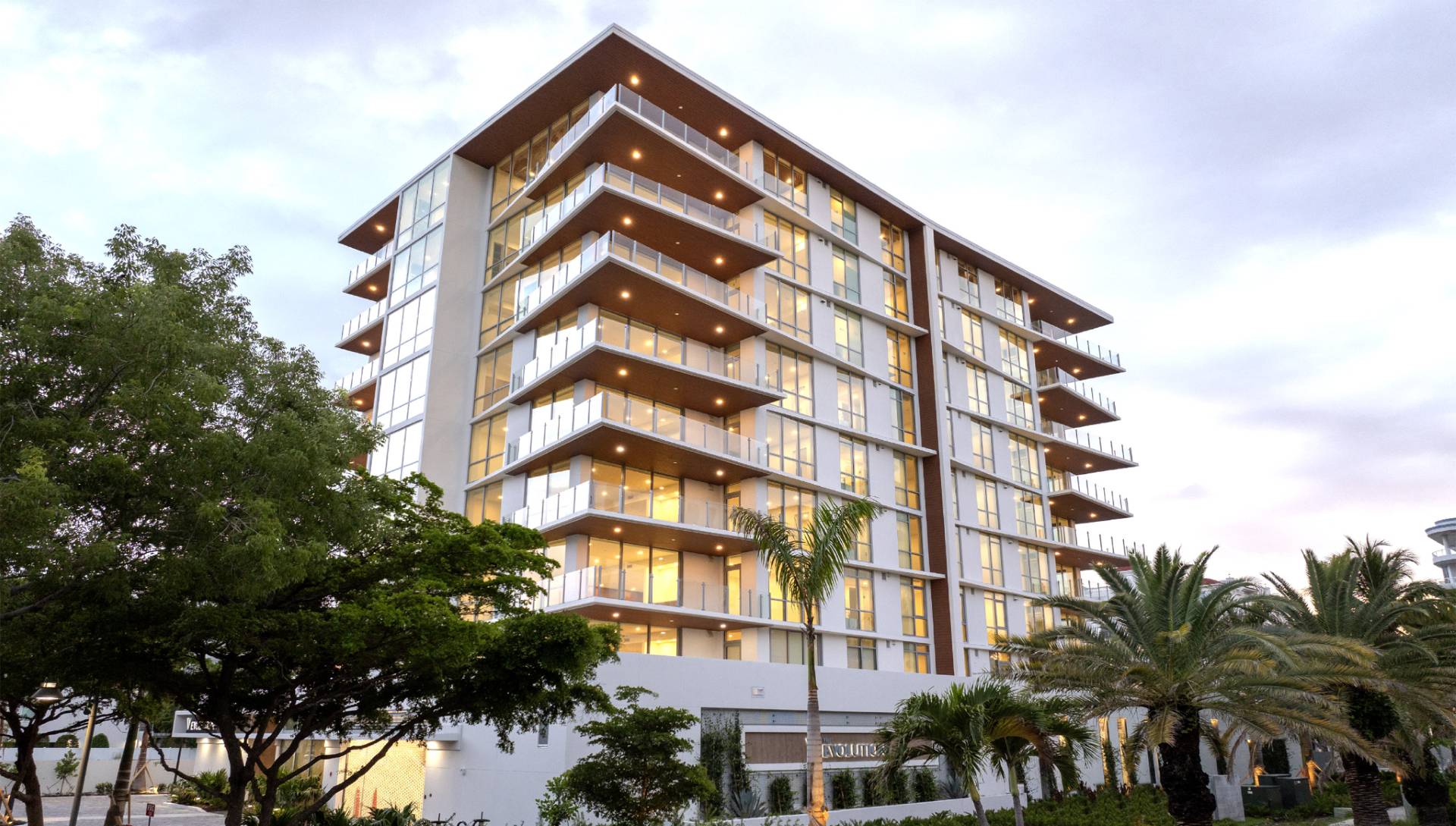 Twilight architectural view of The Evolution residences with illuminated balconies and contemporary glass design in Sarasota