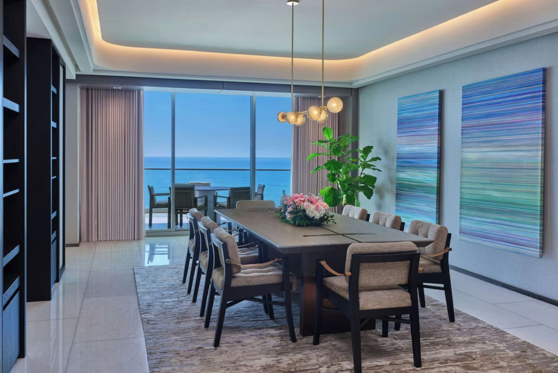 Formal dining room at St. Regis Longboat Key Residences with seating for eight, modern lighting, and panoramic views of the Gulf of Mexico.
