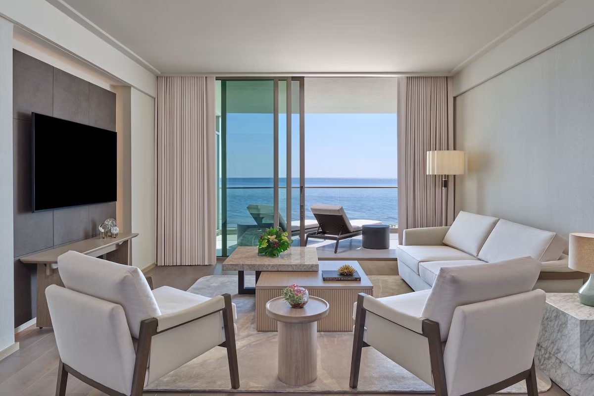 Oceanfront living room at St. Regis Longboat Key Residences with contemporary seating, floor-to-ceiling glass doors, and Gulf of Mexico views.