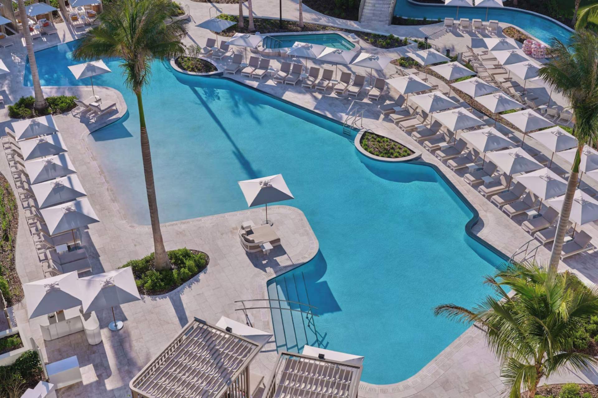 Aerial view of the resort-style swimming pool with private loungers, umbrellas, and cabanas at St. Regis Longboat Key.