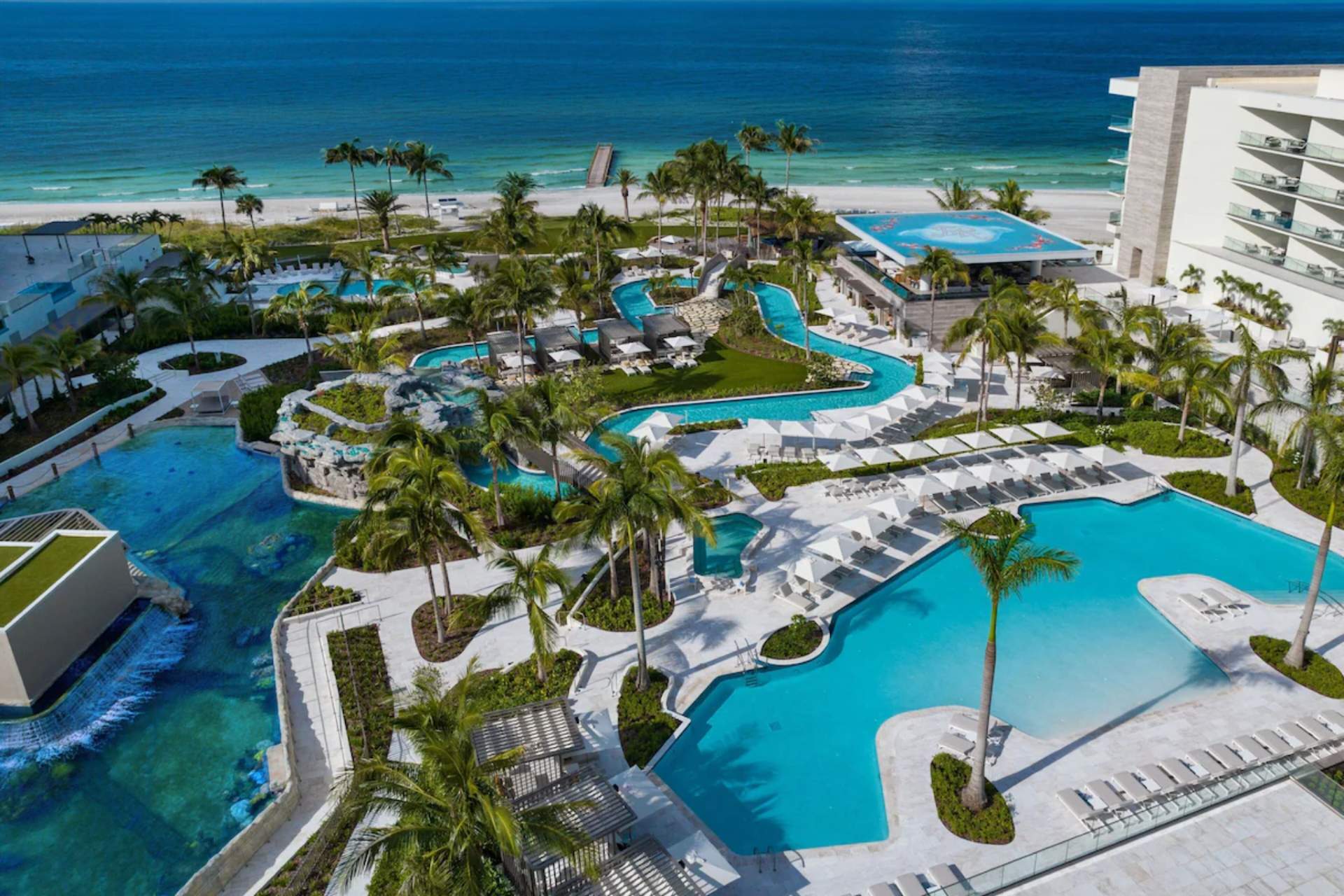 Aerial view of resort pools, lagoon features, and palm landscaping at St. Regis Residences Longboat Key