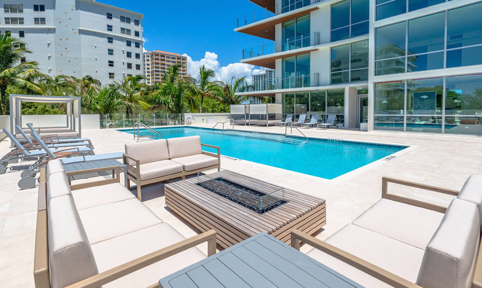 Modern pool terrace with lounge seating, cabanas, and contemporary architecture at The Evolution waterfront residences in Sarasota