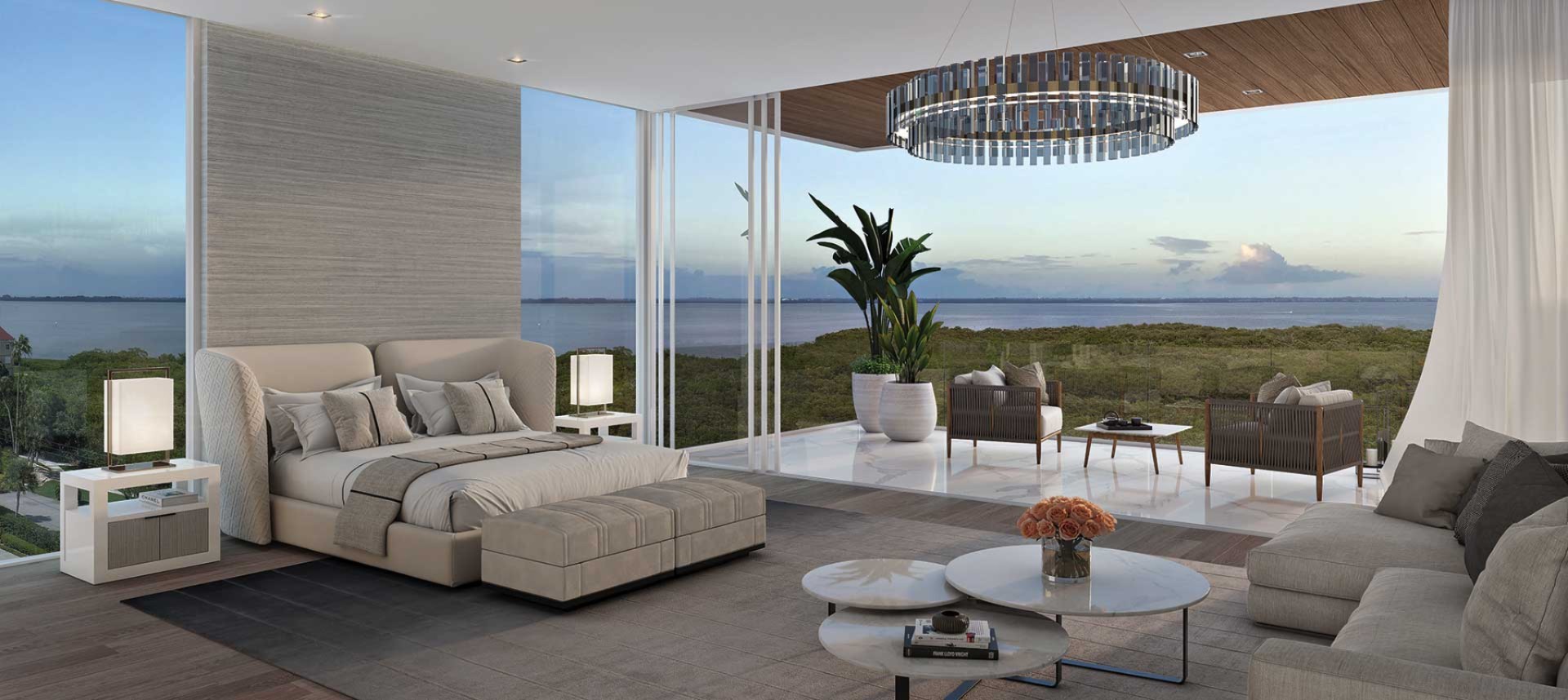 Luxury primary bedroom at Sage Residences on Longboat Key featuring floor-to-ceiling corner glass, modern coastal design, private terrace seating area, and sweeping water views at sunset.