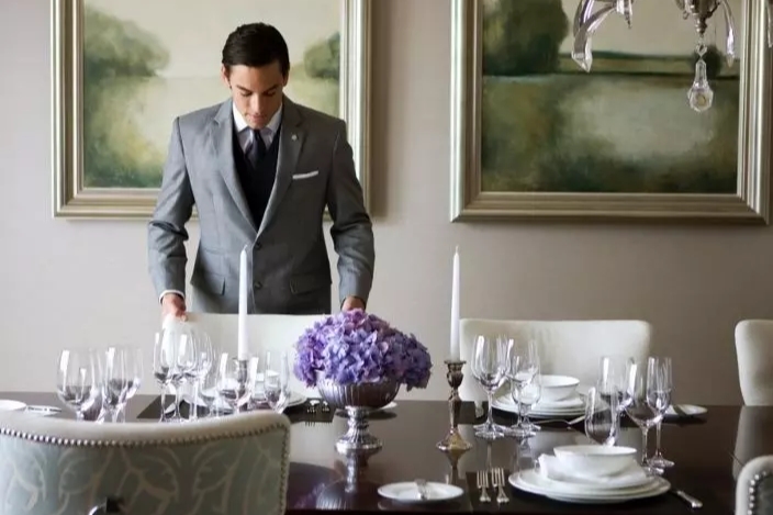 St. Regis butler providing personalized service by preparing a tailored jacket, reflecting the brand’s iconic tradition of refined luxury and attentive residential hospitality.