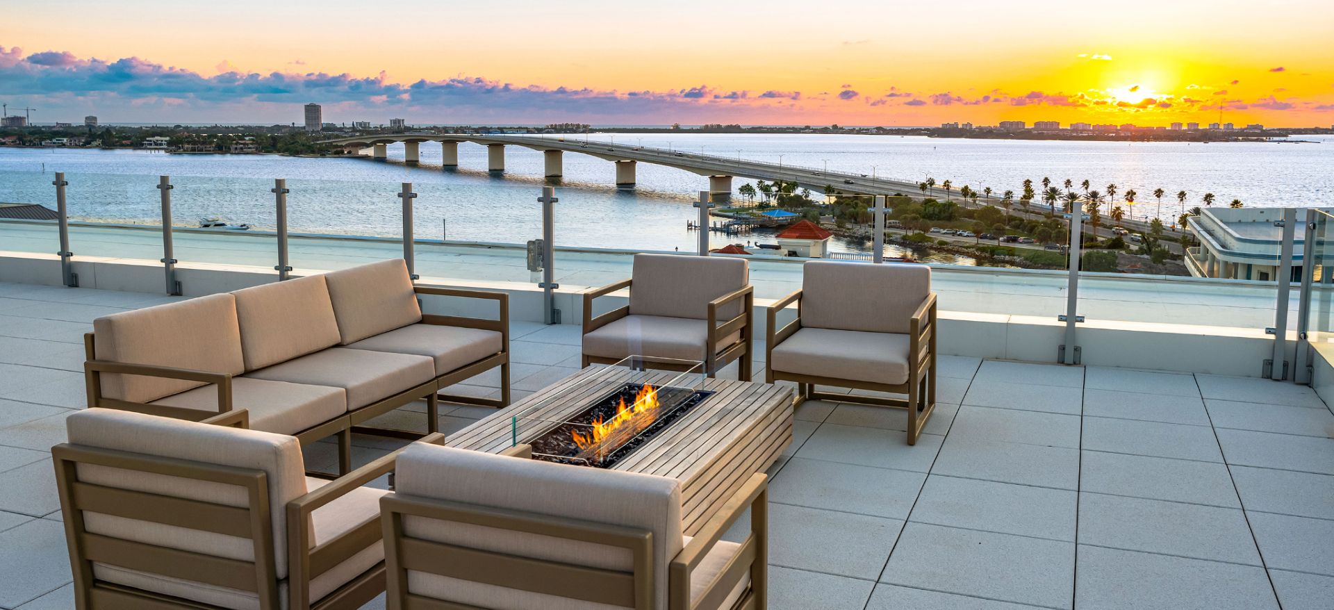 Private rooftop seating area with fire table overlooking Sarasota Bay and Ringling Bridge at sunset
