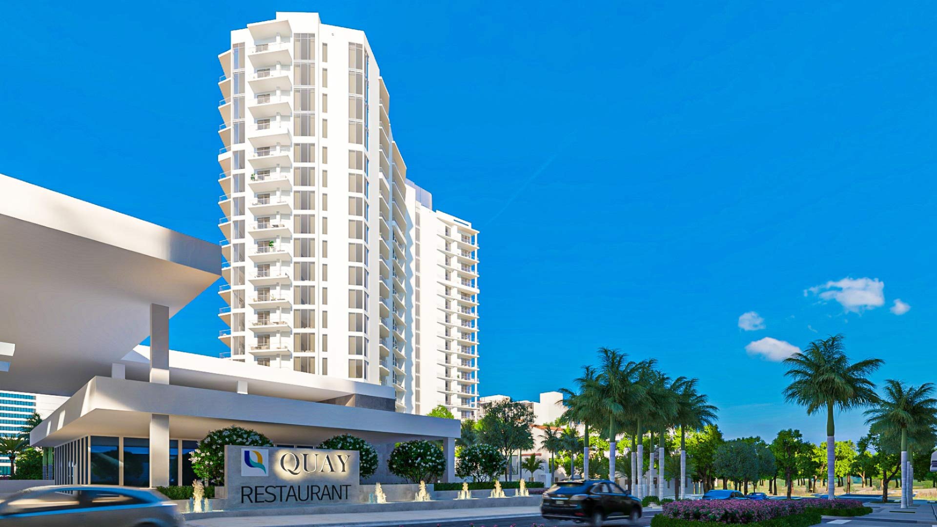 Exterior view of The Ritz-Carlton Residences Sarasota Bay within The Quay district featuring luxury residential tower, palm-lined streetscape, and waterfront setting.