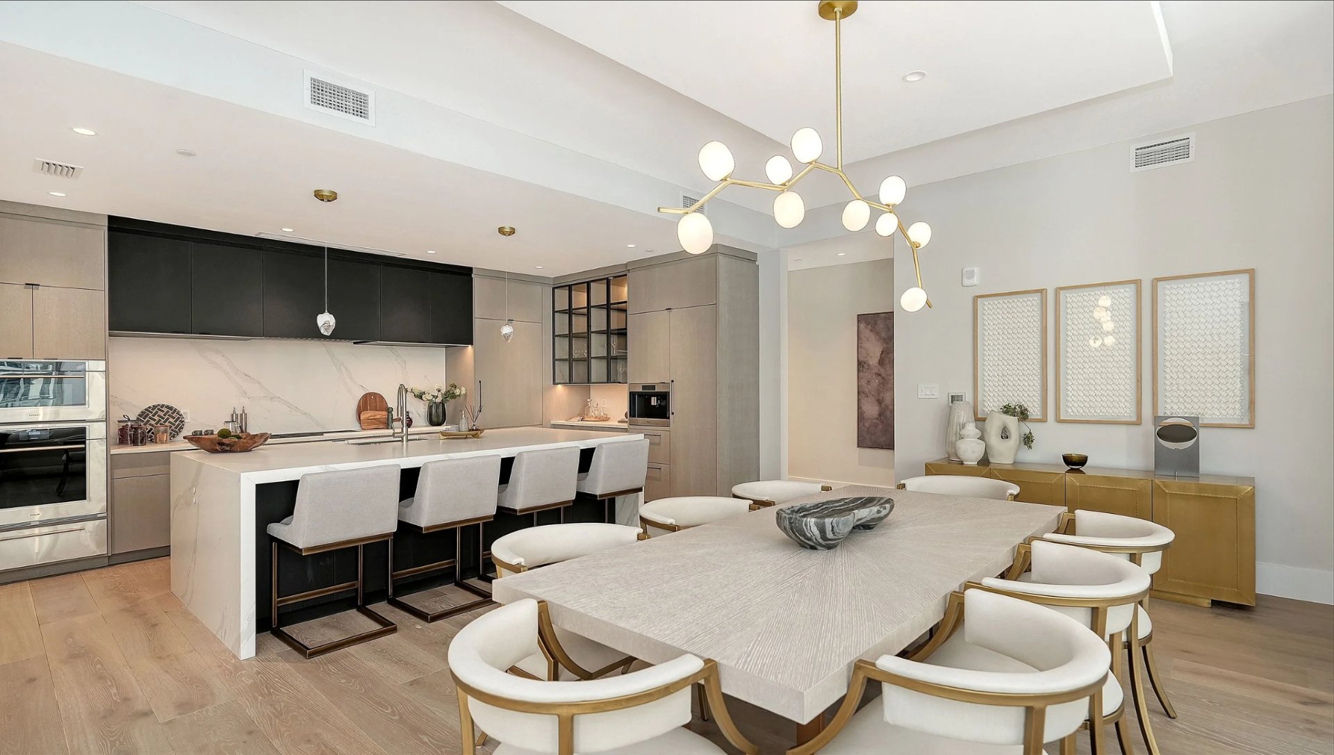 Wide view of modern kitchen with large island and adjacent dining space in Peninsula Sarasota waterfront condo
