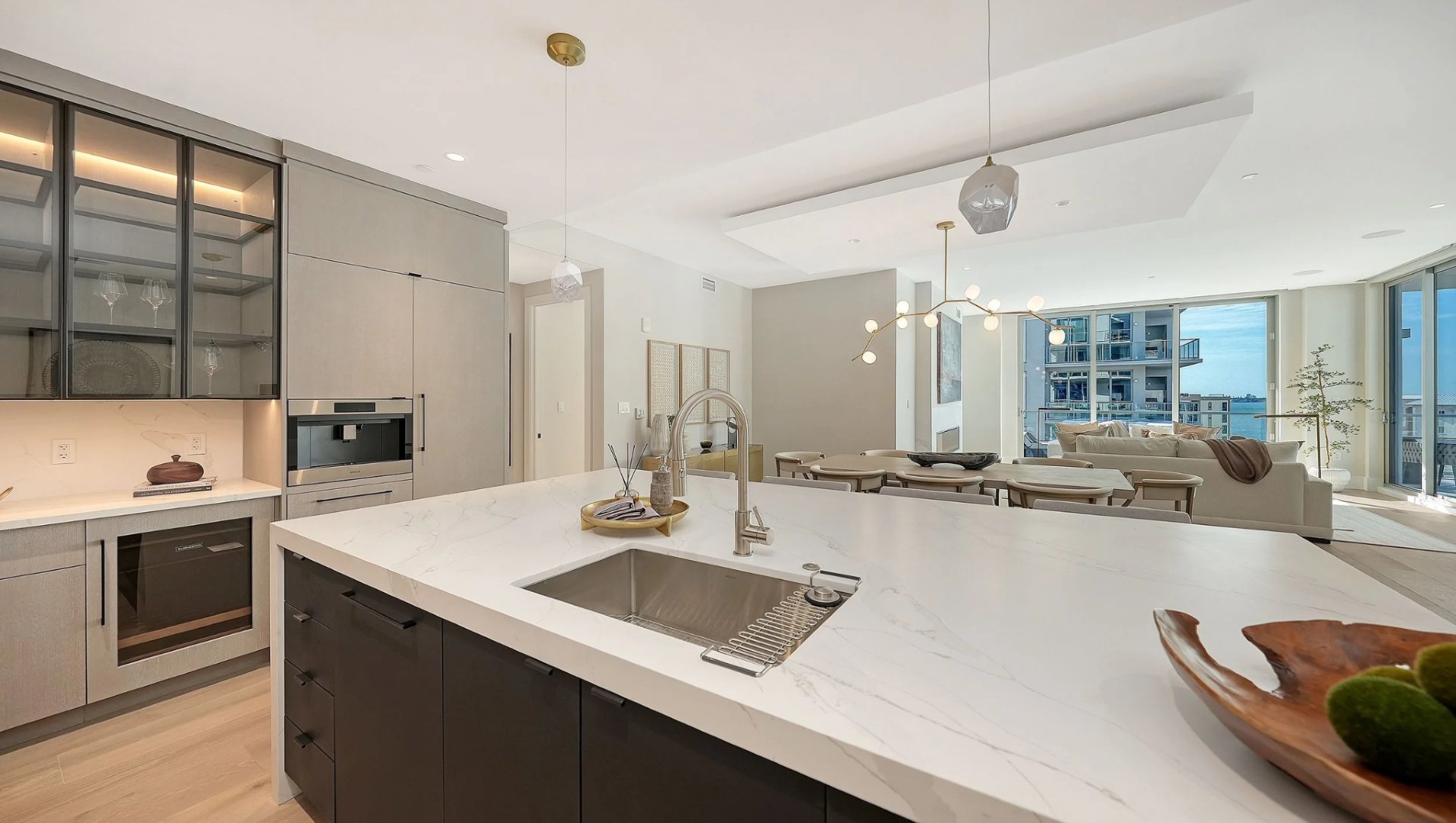 Modern luxury kitchen with marble island and open-concept living area in Peninsula Sarasota waterfront residence