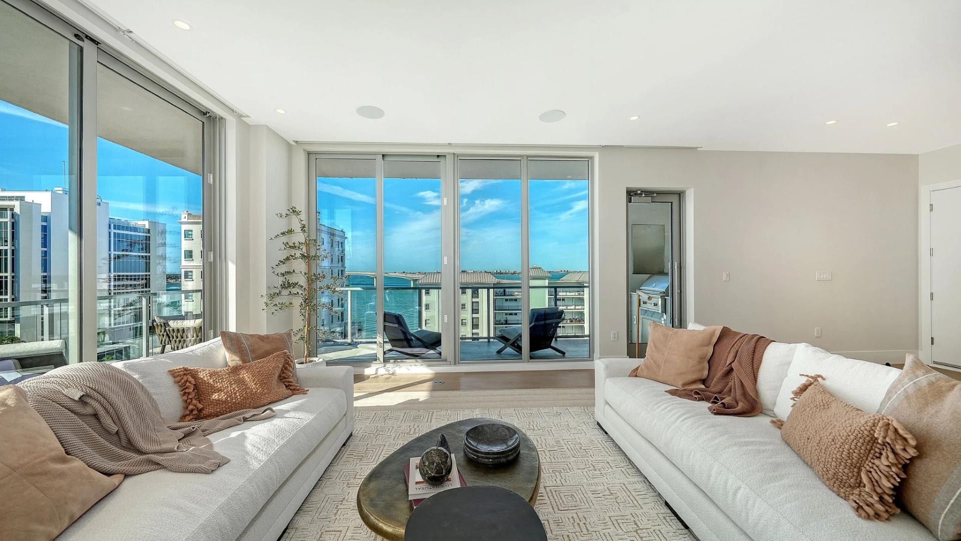 Bright living room with large windows, terrace access, and panoramic Sarasota Bay views in Peninsula Sarasota residence