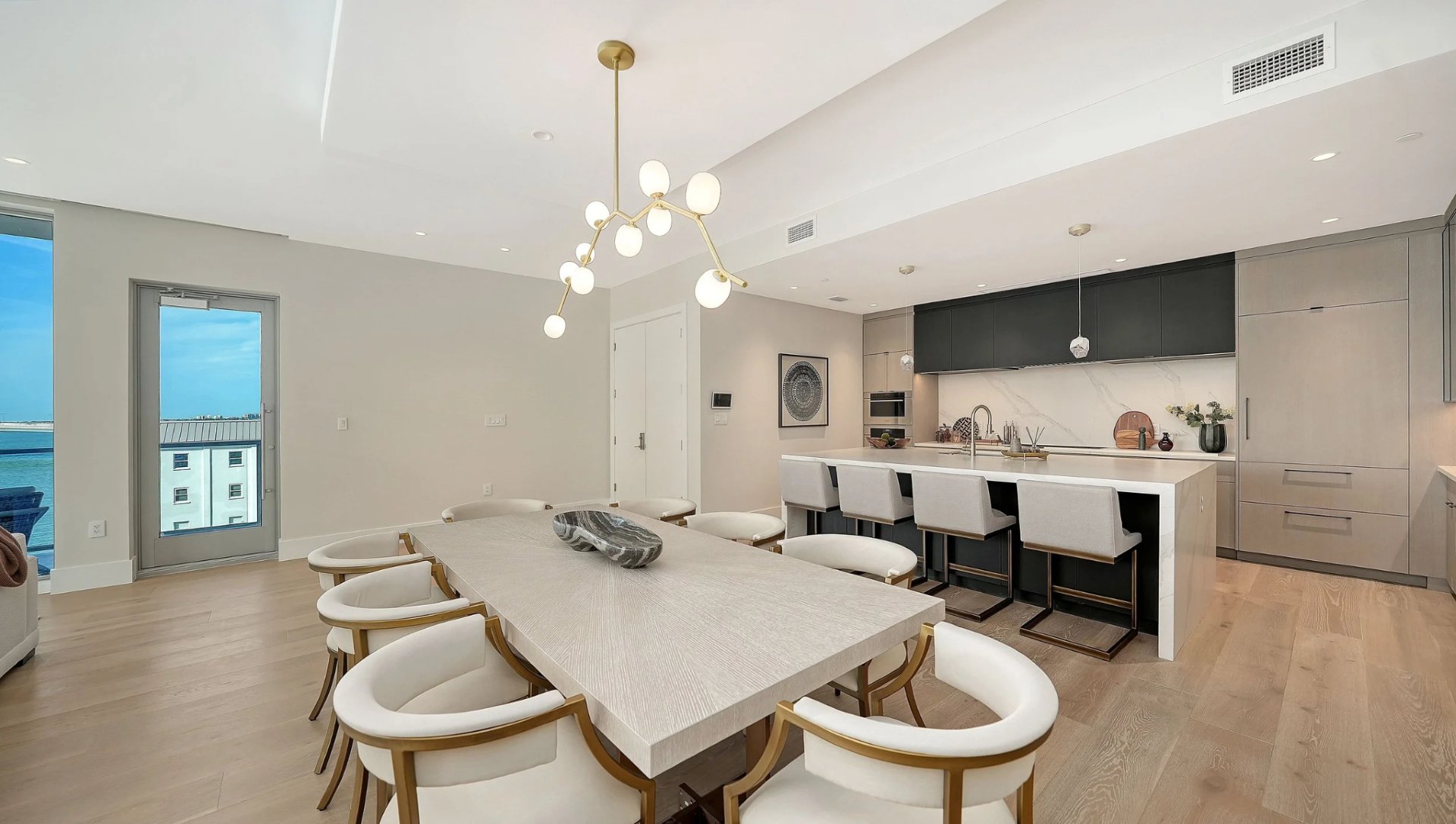 Spacious open kitchen with island seating and dining area in a modern Peninsula Sarasota luxury residence