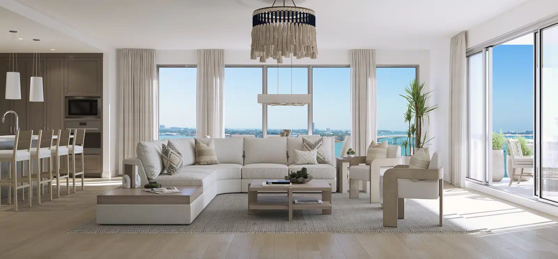 Spacious open-concept living room at The Owen Sarasota featuring floor-to-ceiling windows, coastal-inspired furnishings, and panoramic bay views.