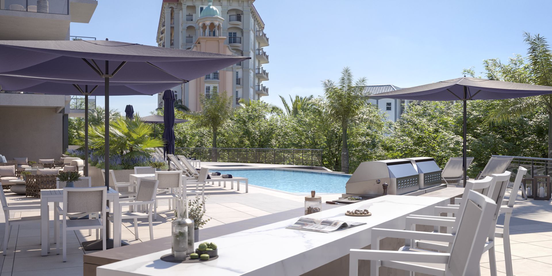 Outdoor kitchen and grilling area at The Owen Sarasota overlooking the pool, with bar seating and shaded dining space.