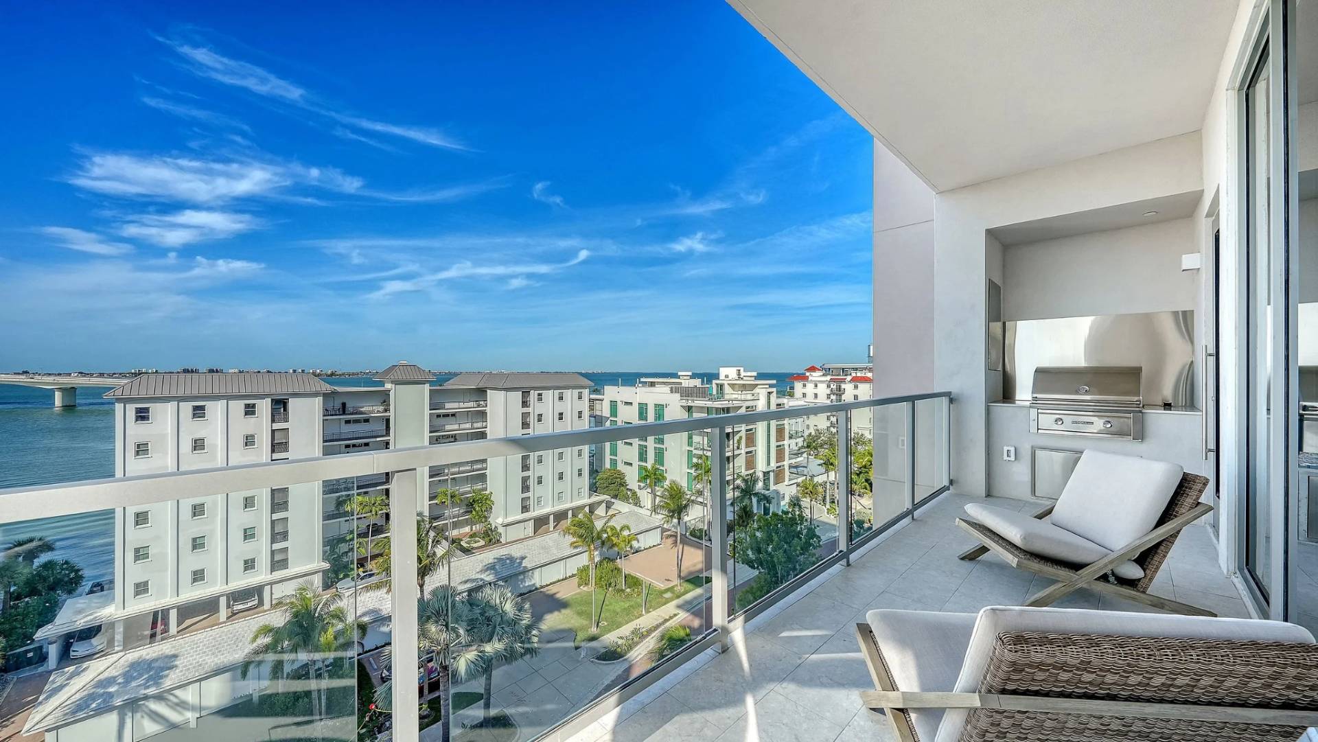 Private waterfront terrace with outdoor kitchen, lounge seating, and Sarasota Bay views at Peninsula Sarasota