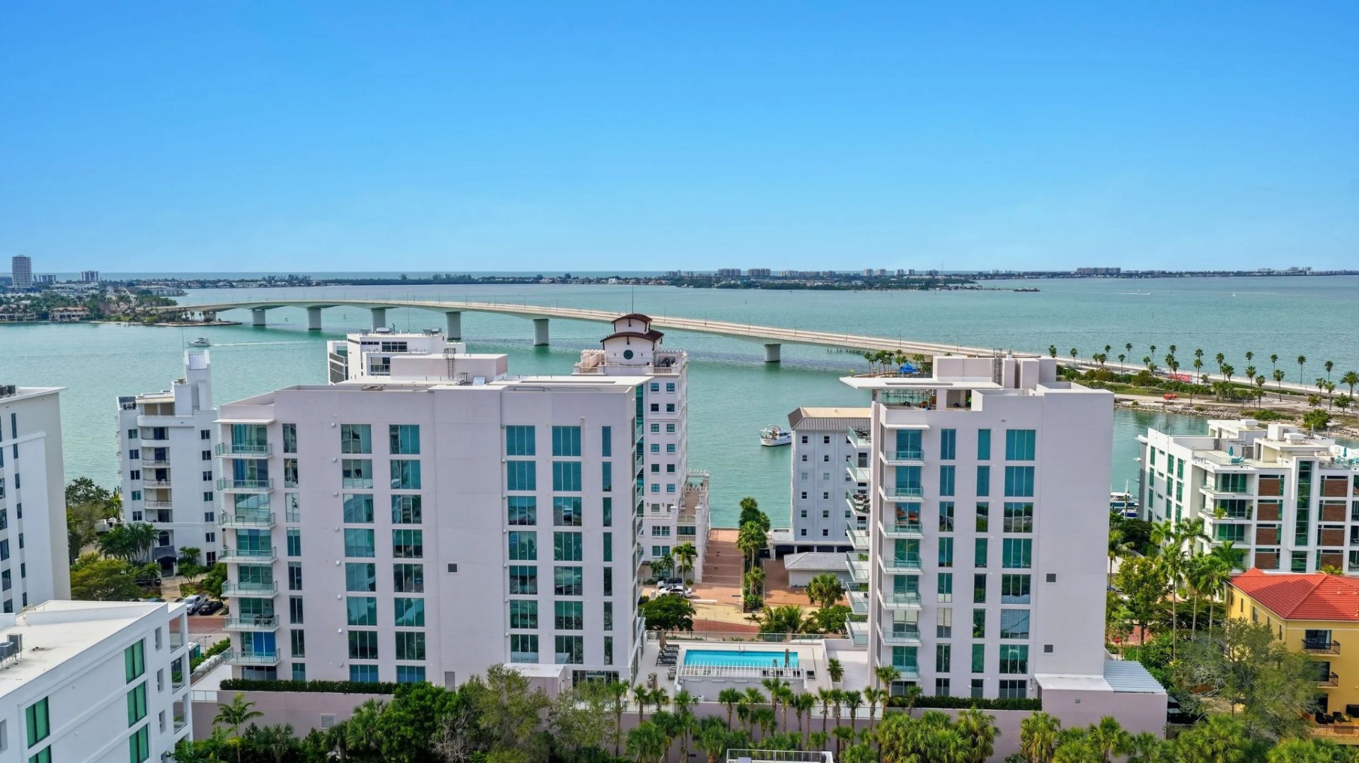 Aerial view of Sarasota Bay with bridge, waterfront condos, and coastal skyline near Peninsula Sarasota
