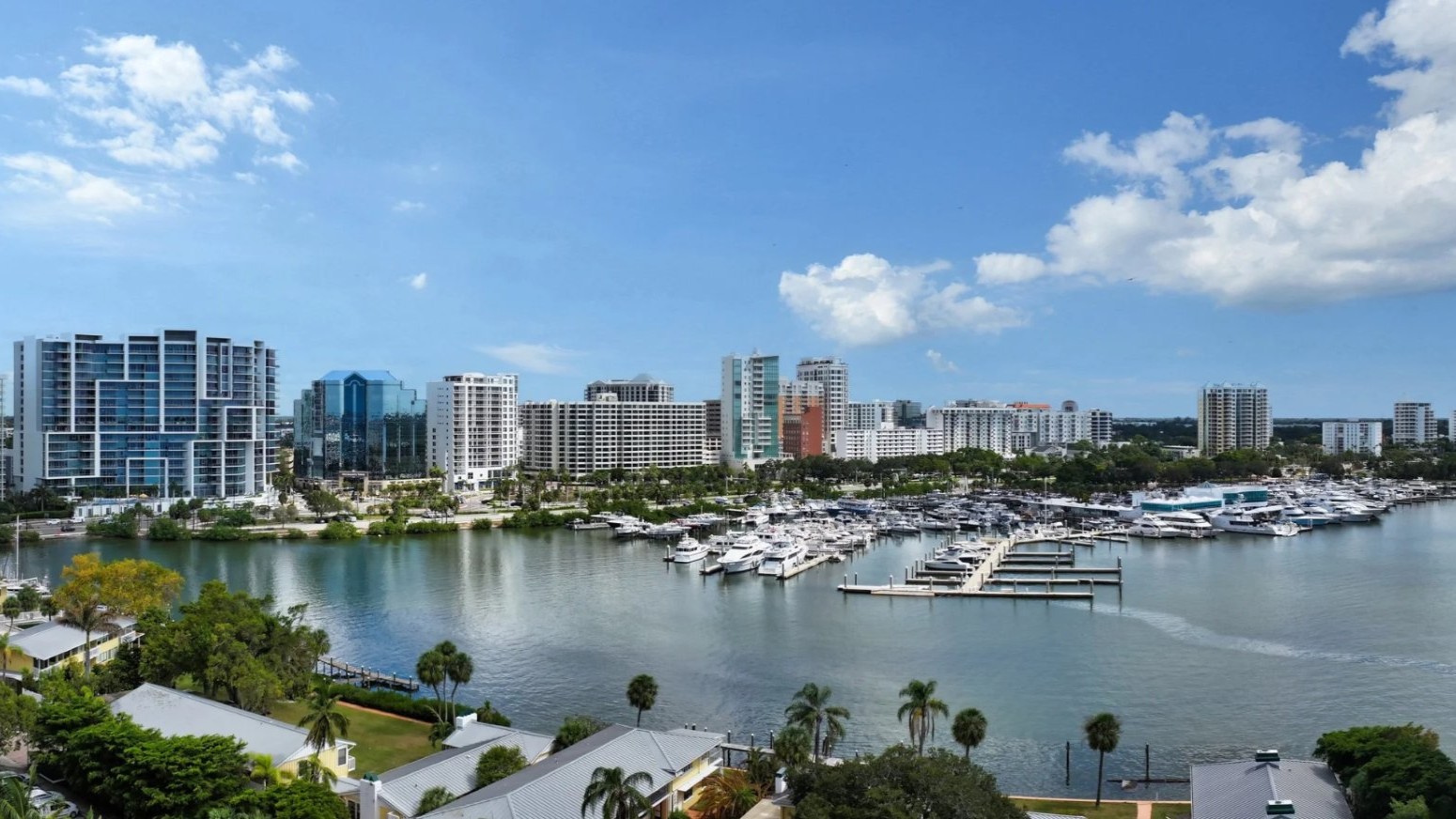 Expansive view of Sarasota Bay marina, waterfront buildings, and boats seen from Peninsula Sarasota