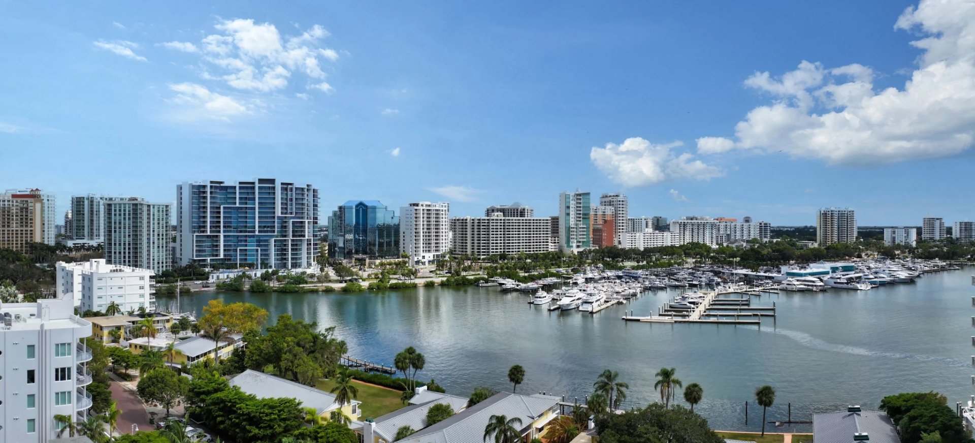 Expansive view of Sarasota Bay marina, waterfront buildings, and boats seen from Peninsula Sarasota