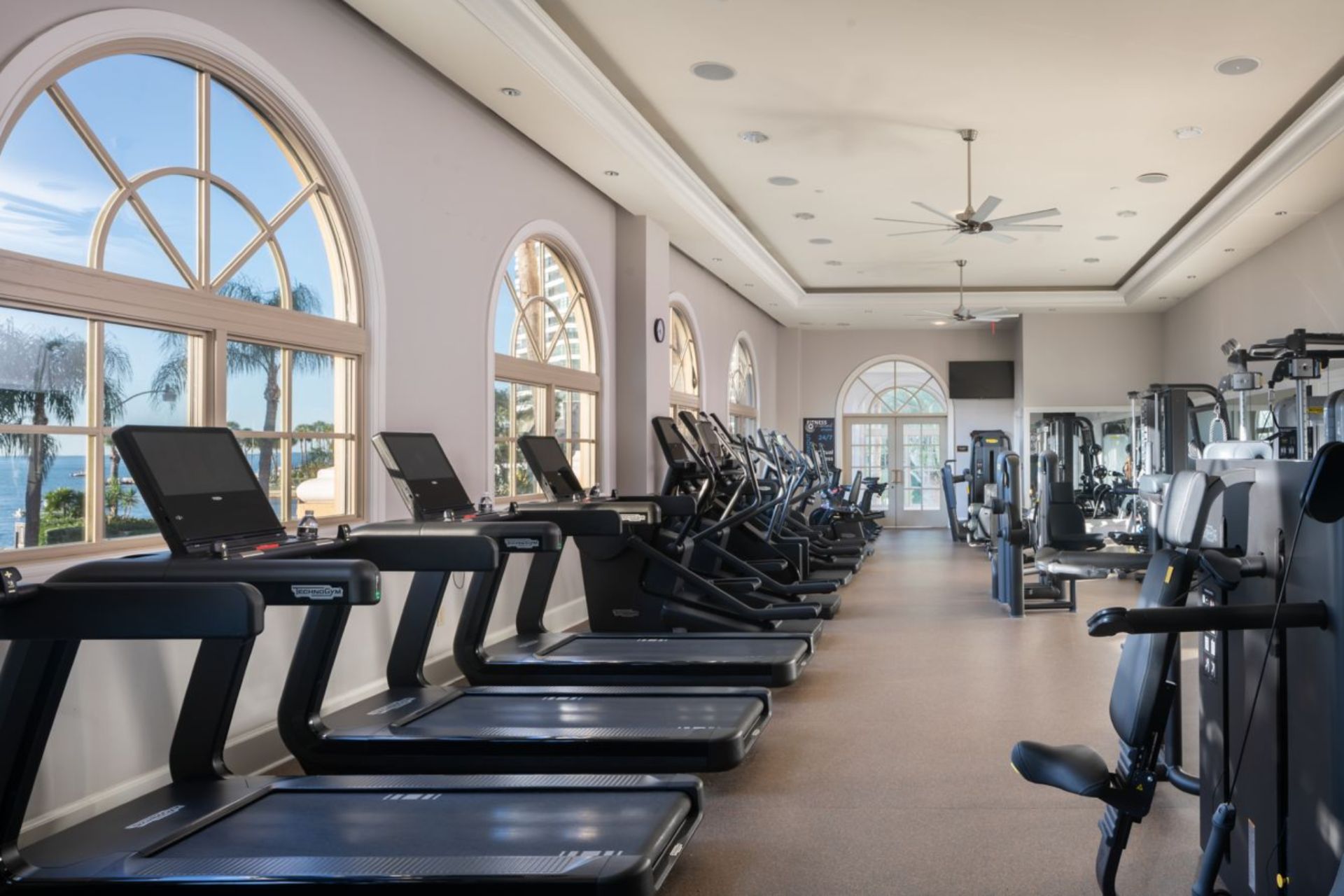 Modern fitness center with treadmills, strength equipment, and large windows overlooking Sarasota Bay at The Ritz-Carlton Sarasota