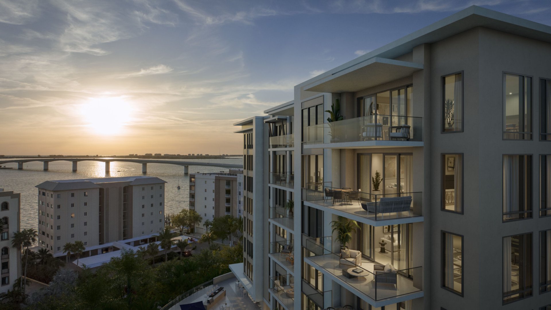 Balcony view from The Owen overlooking Sarasota Bay and John Ringling Bridge at sunset with waterfront skyline.