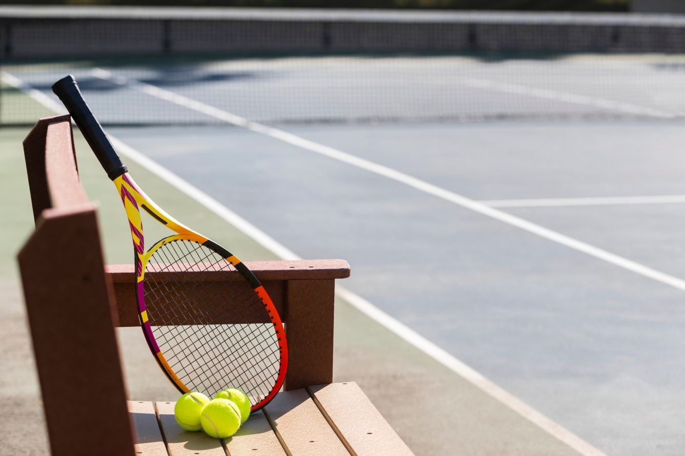 Tennis racquet and balls on court at The Ritz-Carlton Sarasota with professional-grade facilities
