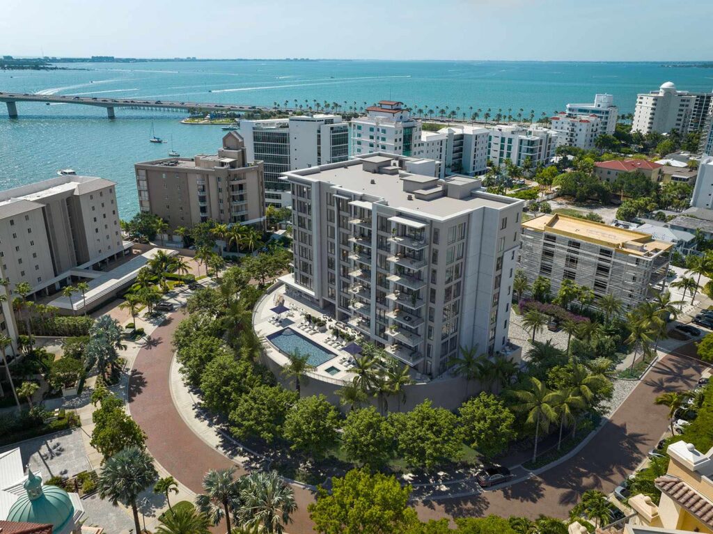 Daytime aerial of The Owen showcasing luxury residences, pool deck, and lush landscaping in Sarasota.