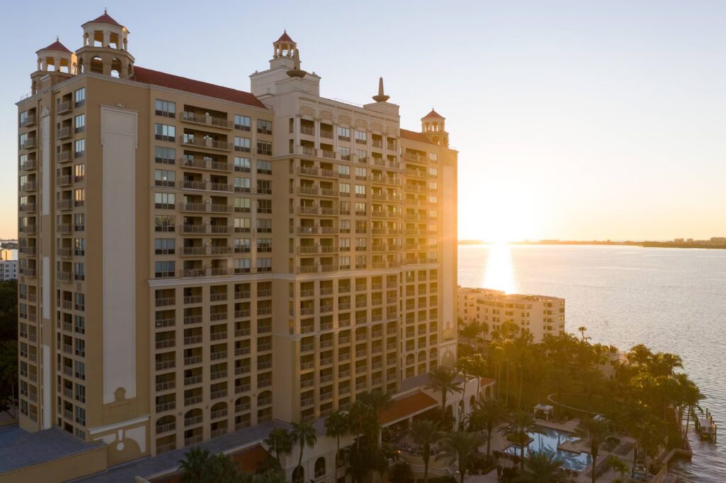 Luxury waterfront tower of The Ritz-Carlton Sarasota at sunset with golden light reflecting over Sarasota Bay