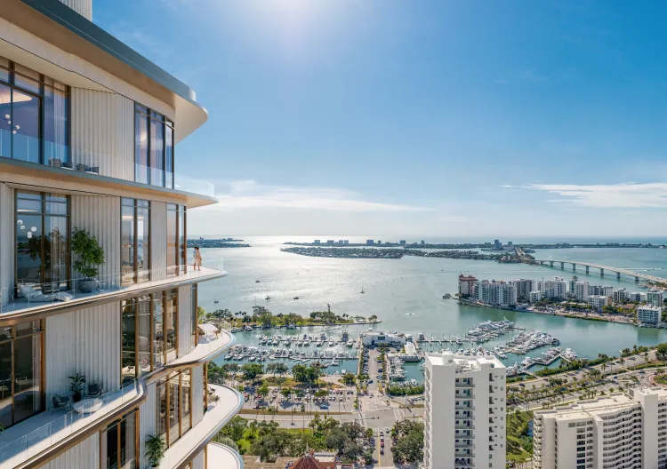 Luxury waterfront view from Waldorf Astoria Residences Sarasota overlooking Sarasota Bay, marina, and skyline with expansive glass balconies and modern architecture