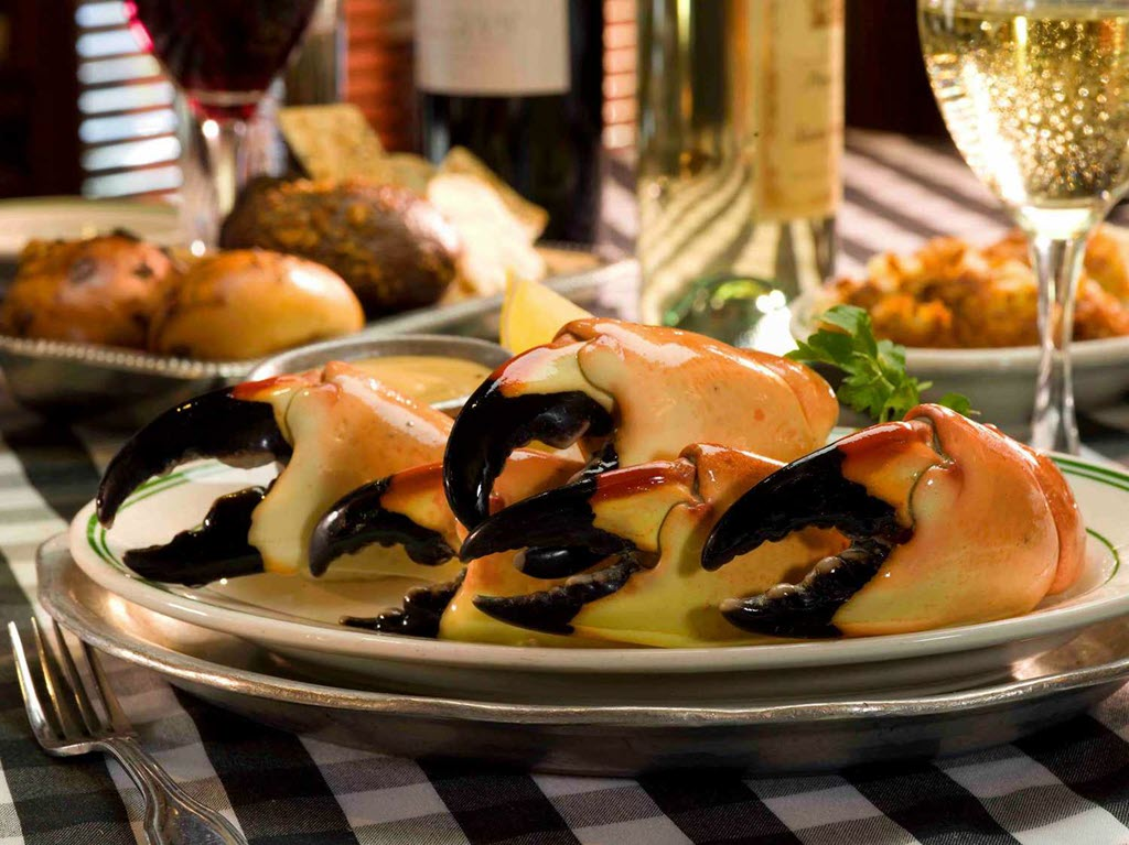 A plate of freshly cooked stone crab claws with a glass of wine